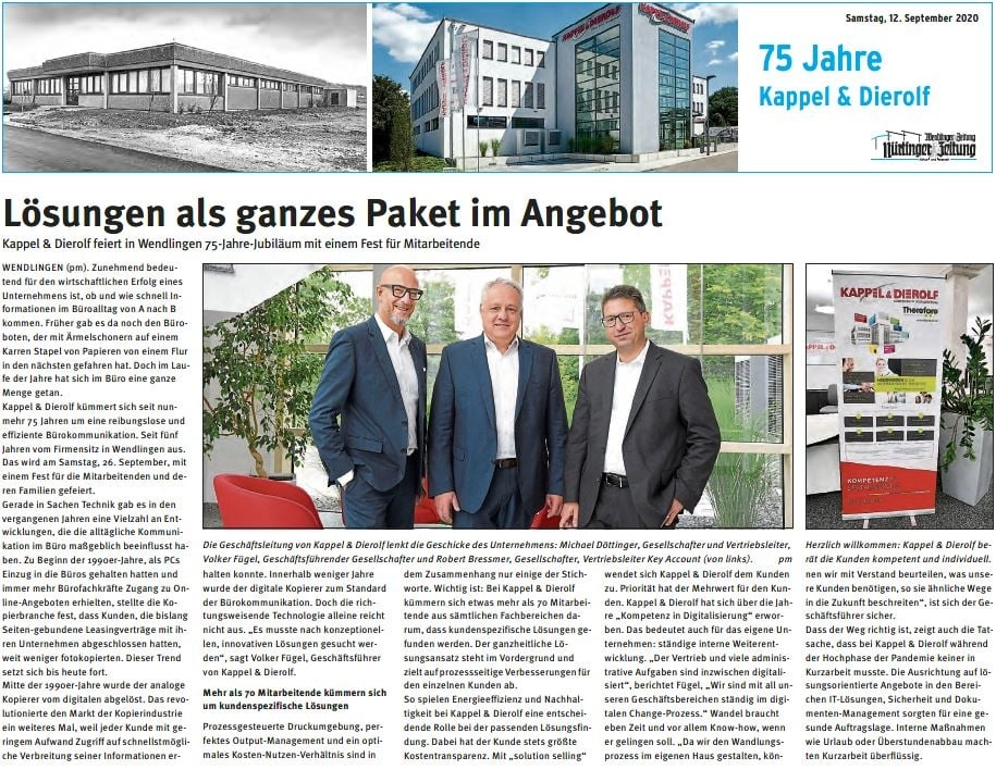 Drei Männer stehen lächelnd vor einem Bürofenster, neben einem Roll-Up mit Kappel & Dierolf Logo, zum 75-jährigen Jubiläum.