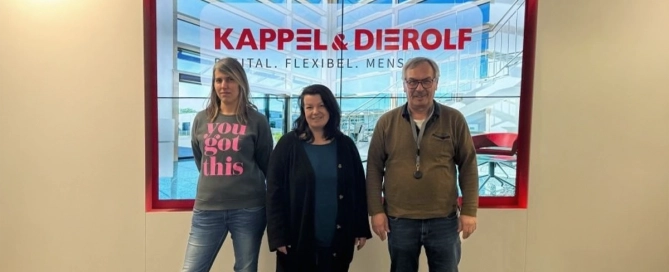 Drei Personen vor einem Bildschirm mit Kappel & Dierolf Logo, in einem modernen Büro.