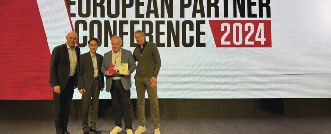 Vier Männer posieren vor einem Schild European Partner Conference 2024 mit einer Auszeichnung.