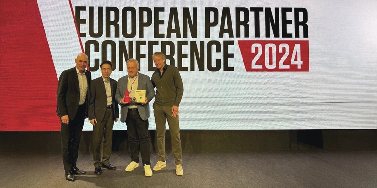 Vier Männer posieren vor einem Schild European Partner Conference 2024 mit einer Auszeichnung.