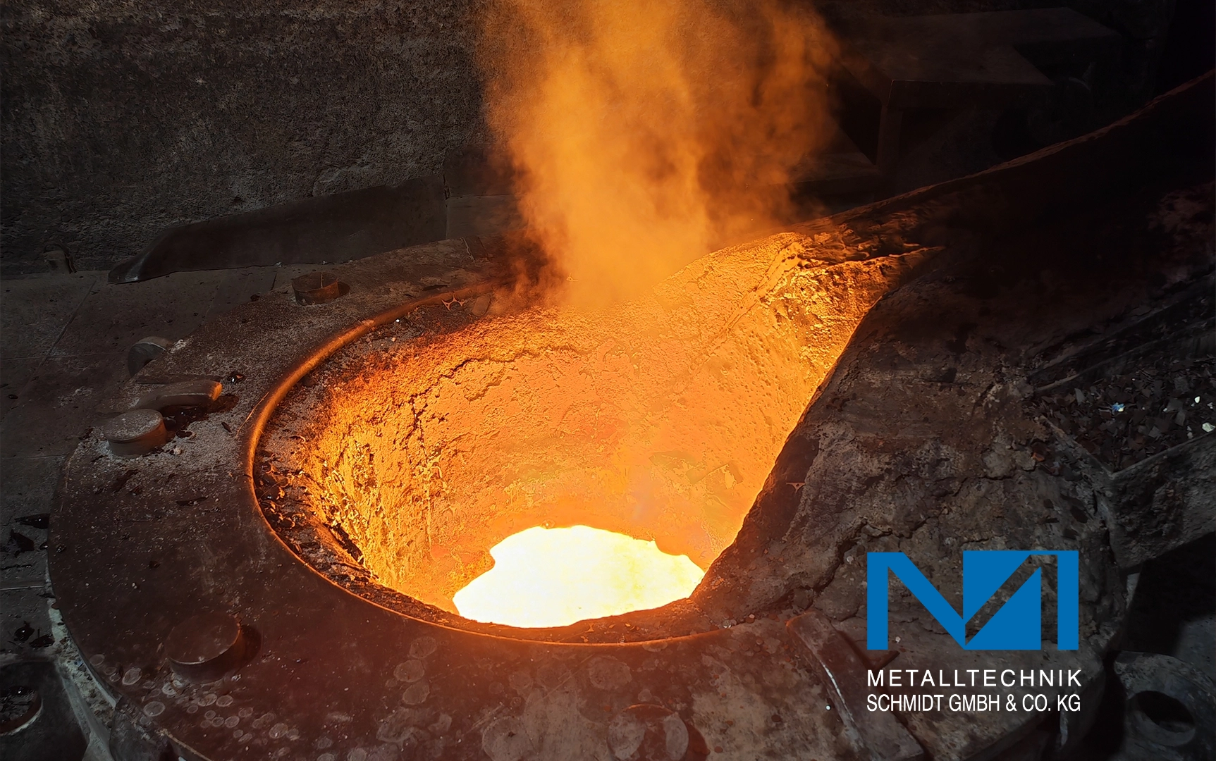 Kappel-Dierolf_Cases_Metallbau-Schmidt Schmelzofen mit flüssigem Metall im Inneren, orange beleuchtet, zieht sich Dampf hoch. Umgebung rau und industriell.
