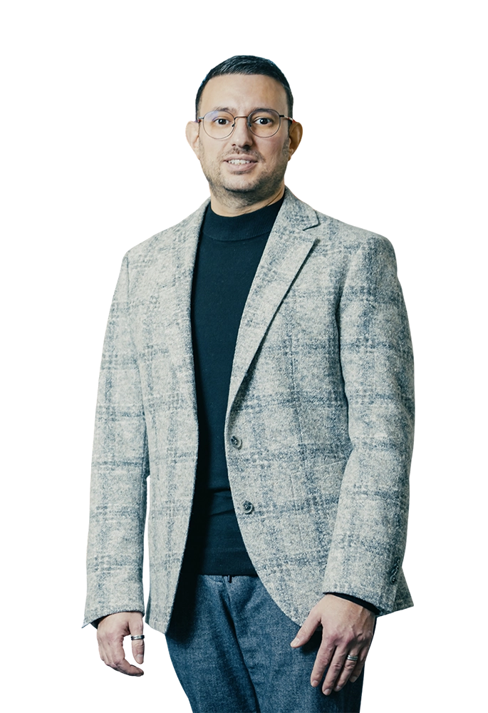 Eine Person in grauem Sakko und schwarzem Rollkragenpullover, schaut freundlich in die Kamera.