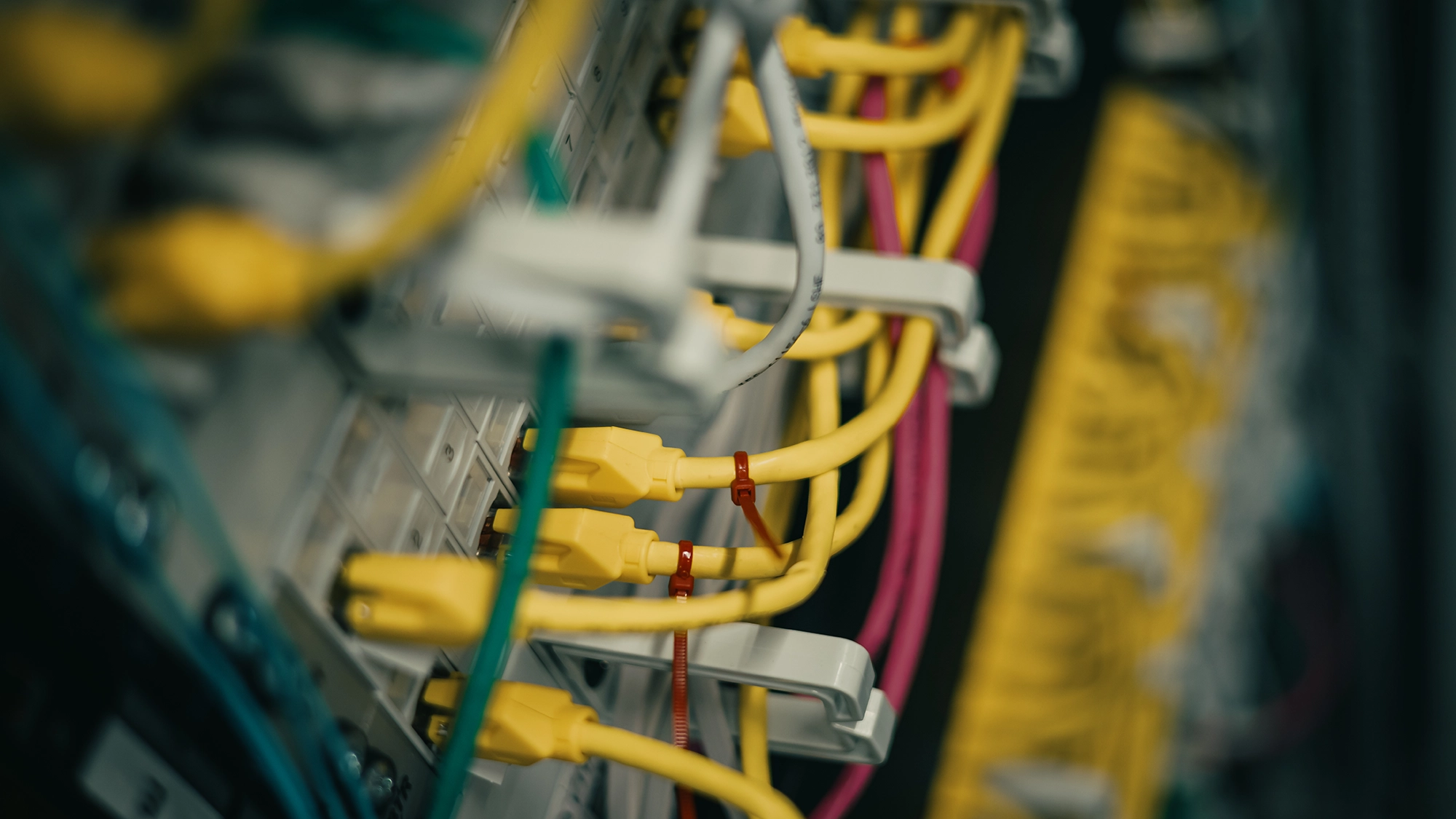 Gelbe und rosa Netzwerkkabel in einem Server-Rack, verbunden mit einem Patch-Panel.