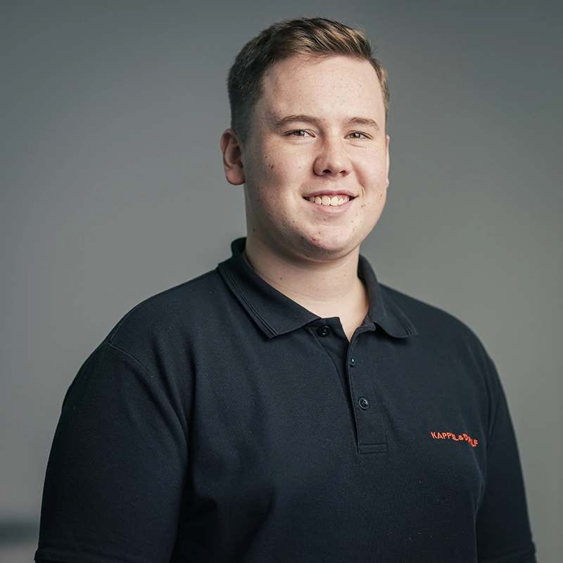 Ich weiß nicht, wer auf dem Bild ist. Es zeigt einen lächelnden Mann in einem schwarzen Poloshirt vor grauem Hintergrund.