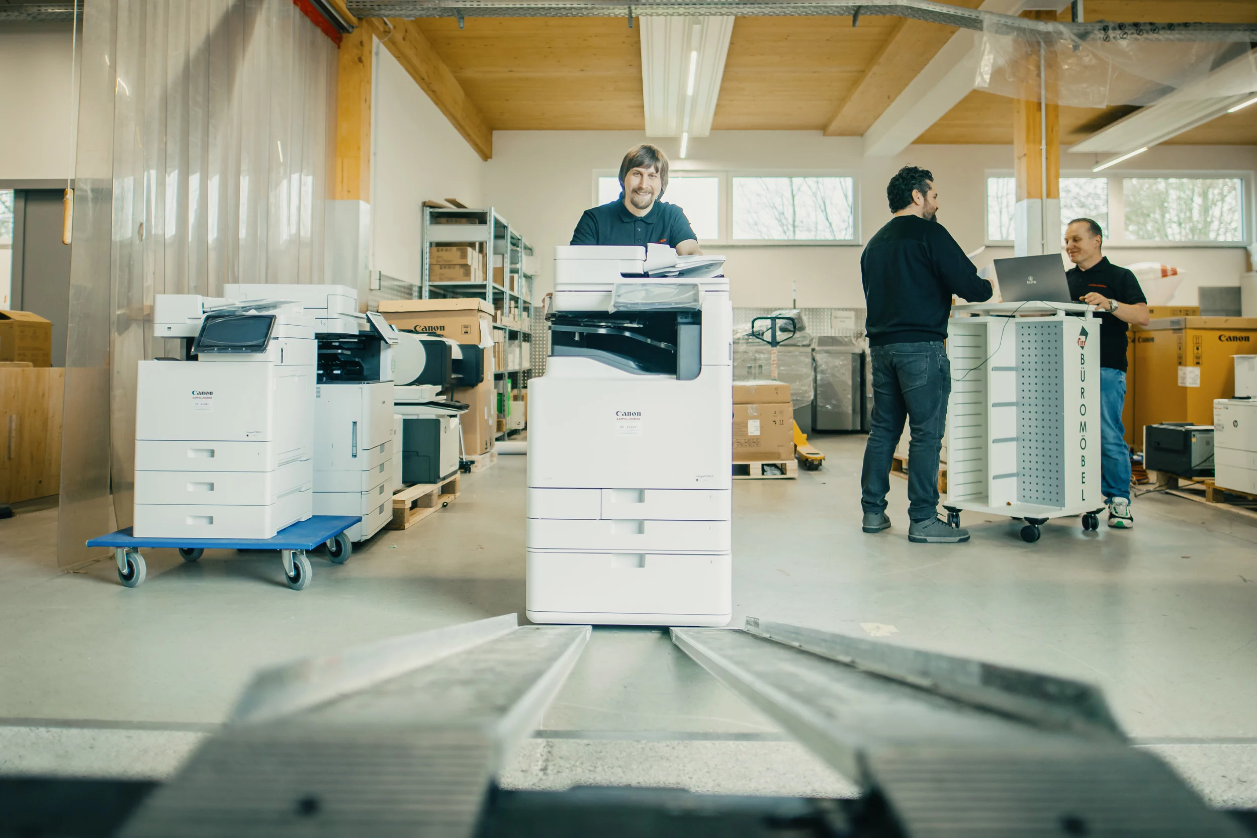 Mann mit Headset arbeitet an einem Computer in einem Büro, Licht strömt durch das Fenster.